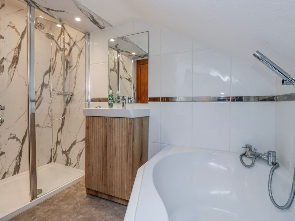 A bathroom with a shower, bathtub, and sink at The Thistles in Bowness-On-Windermere