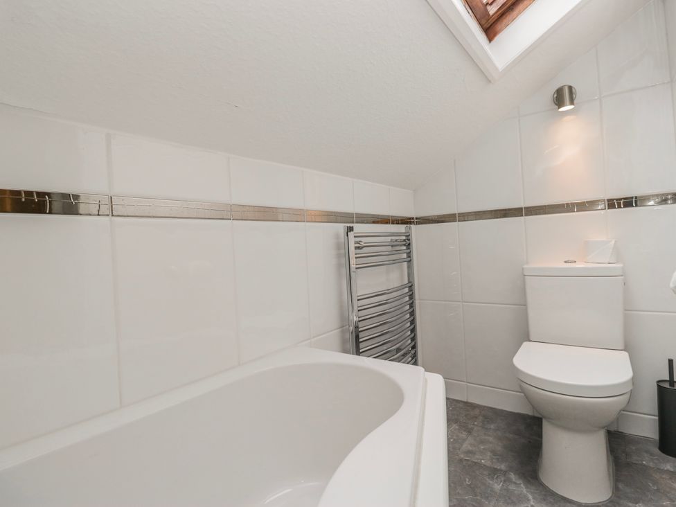 A bathroom with a bathtub and a toilet at The Thistles Bowness-On-Windermere
