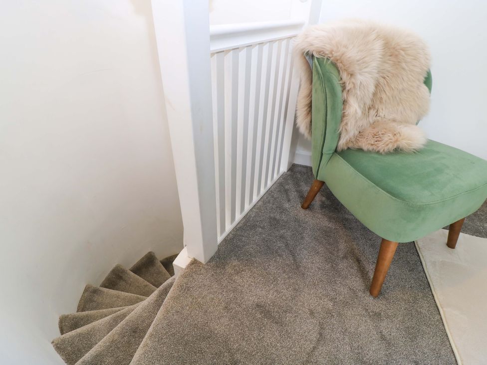 A carpeted stairway and a green chair with a fur throw on it near Cirencester