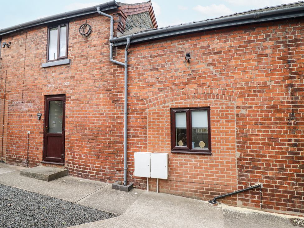 An exterior view of a brick wall with a door and window at 1 Y Llew Llandinam