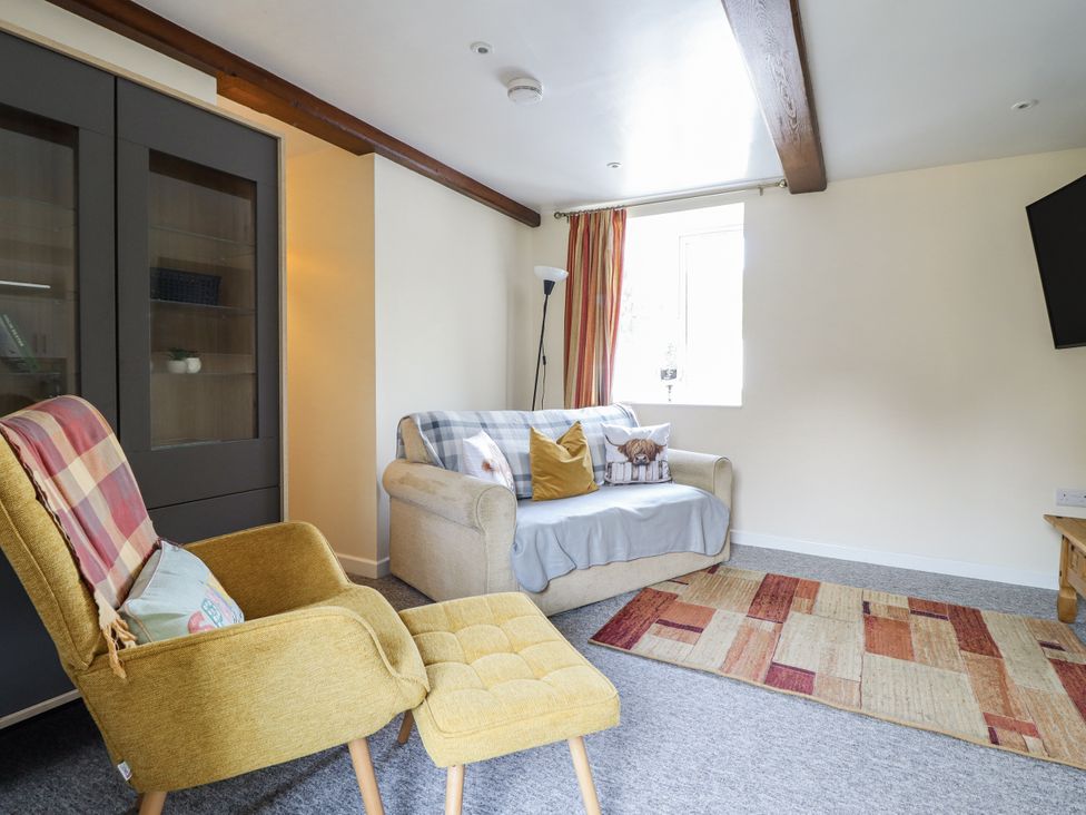 A living room with a sofa and armchair at 1 Y Llew in Llandinam