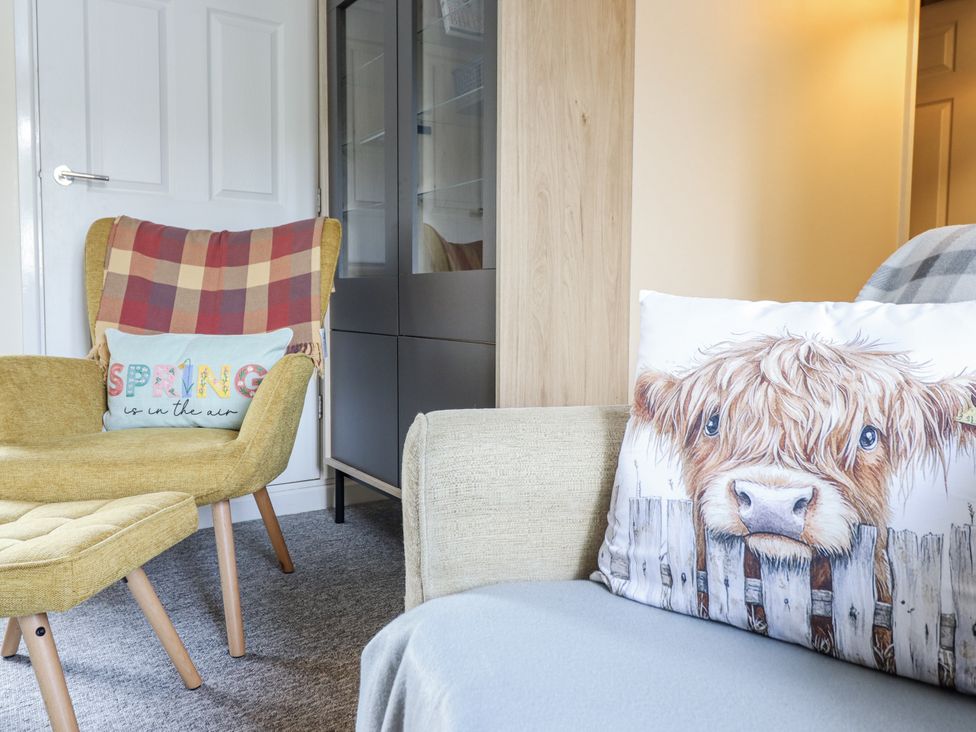 A living room with an armchair, sofa, and cabinet at 1 Y Llew in Llandinam