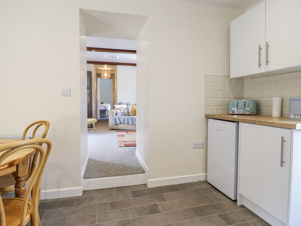 A kitchen with a dining table and refrigerator at 1 Y Llew in Llandinam