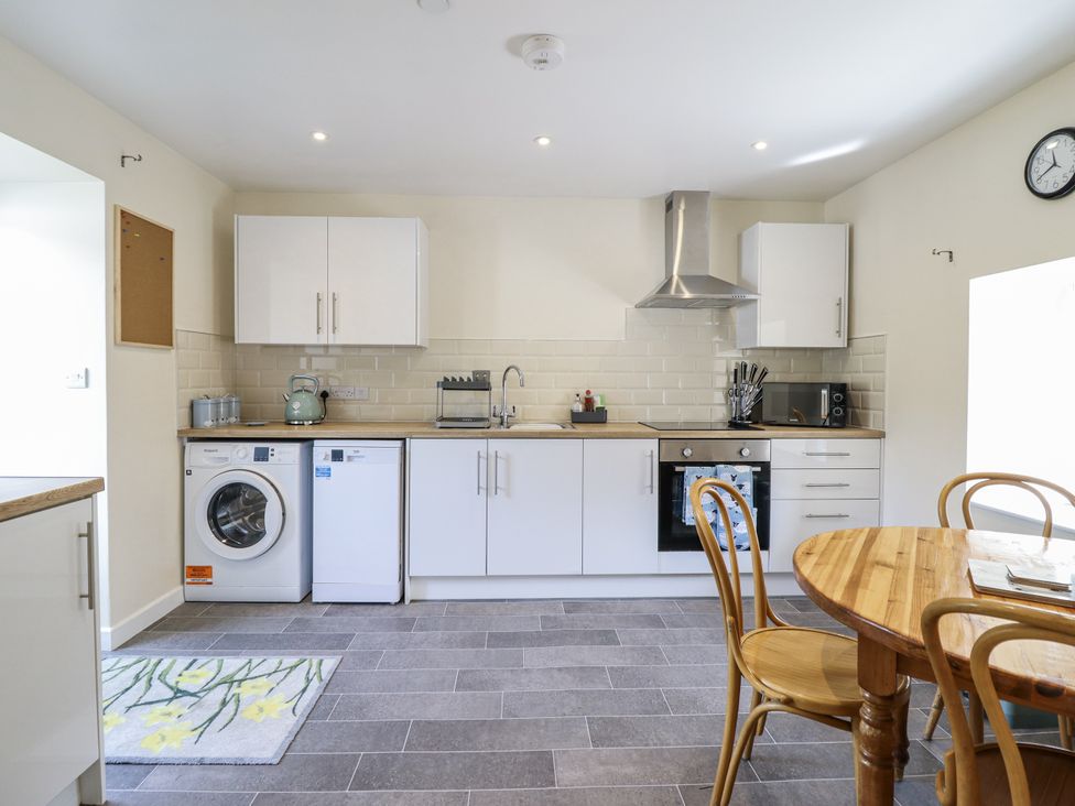 A kitchen with appliances and dining table at 1 Y Llew in Llandinam