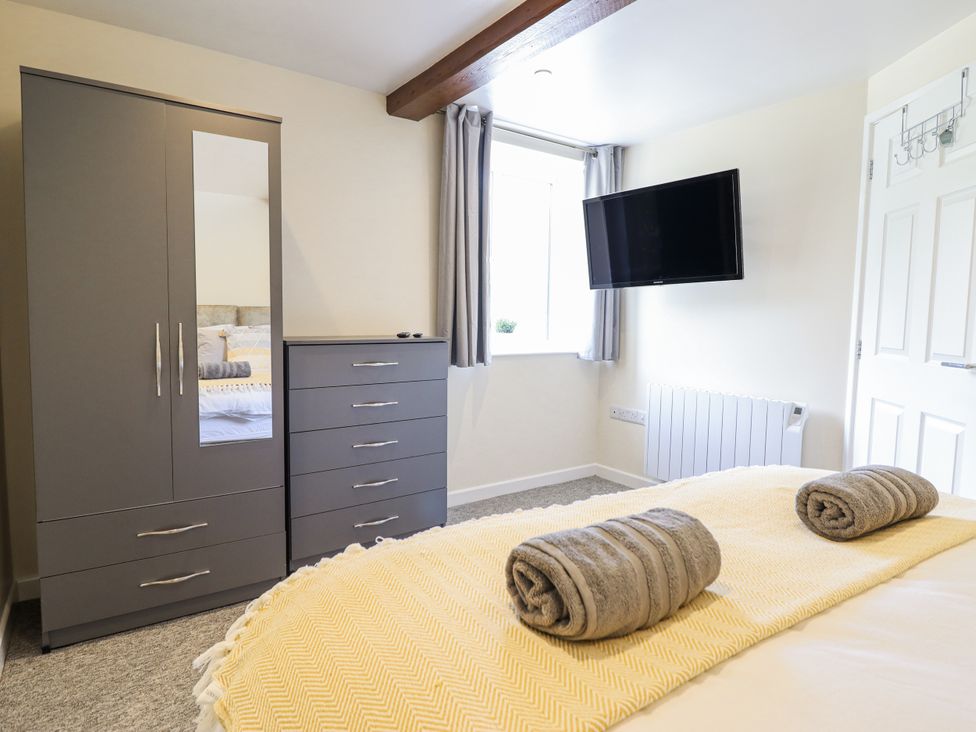 A bedroom with a wardrobe, chest of drawers, and television at 1 Y Llew in Llandinam