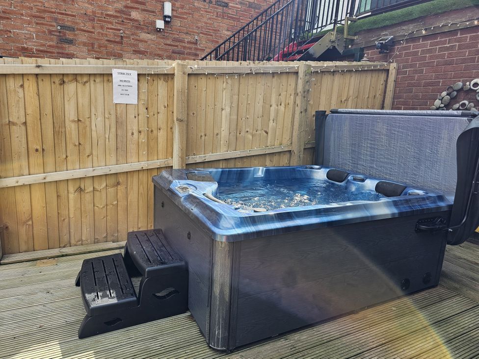 A hot tub with steps next to a wooden fence at Circus Circus, Holywell