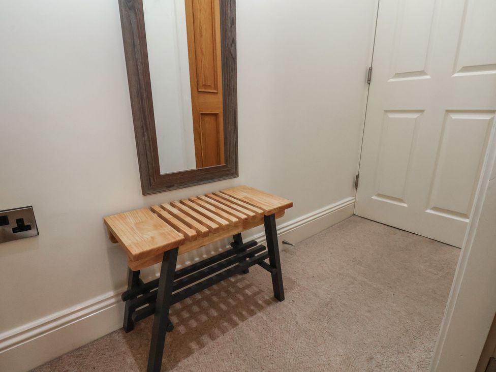A hallway with a bench and a mirror at Jolly Roger in Whitby