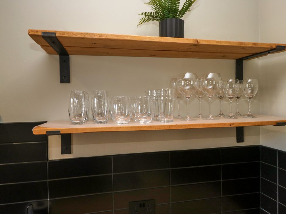 A kitchen shelf with stacked glasses and wine glasses at 5 Thornbarrow Road