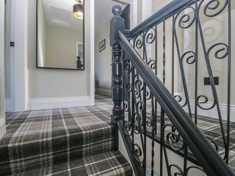 A staircase with a handrail and a mirror in a hallway at 5 Thornbarrow Road