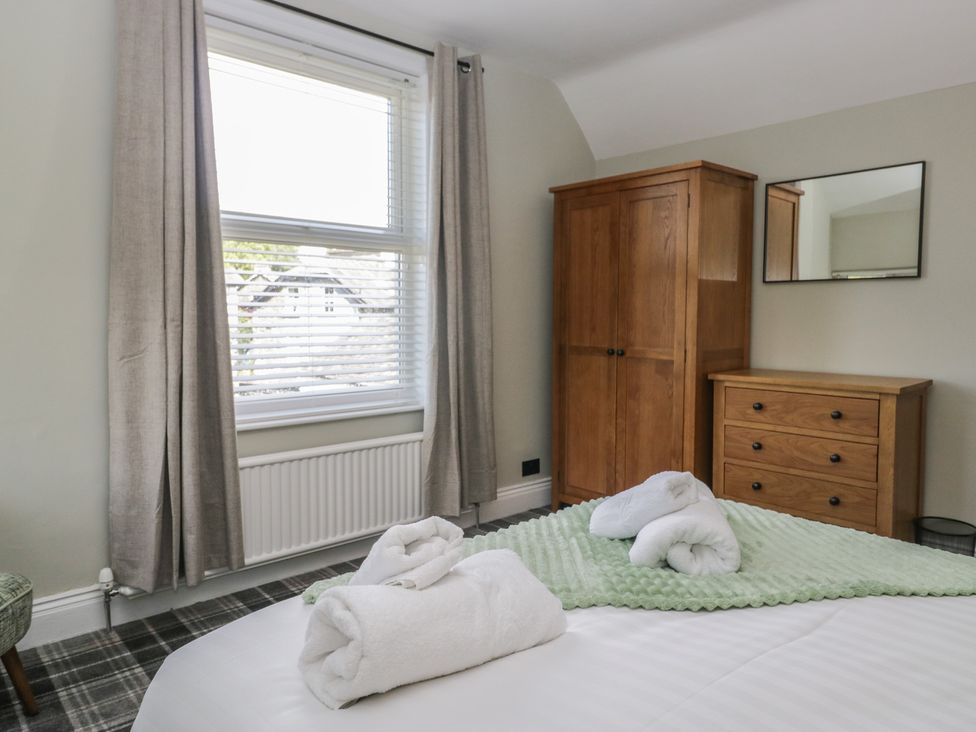 A bedroom with a bed, wardrobe, and a mirror at 5 Thornbarrow Road