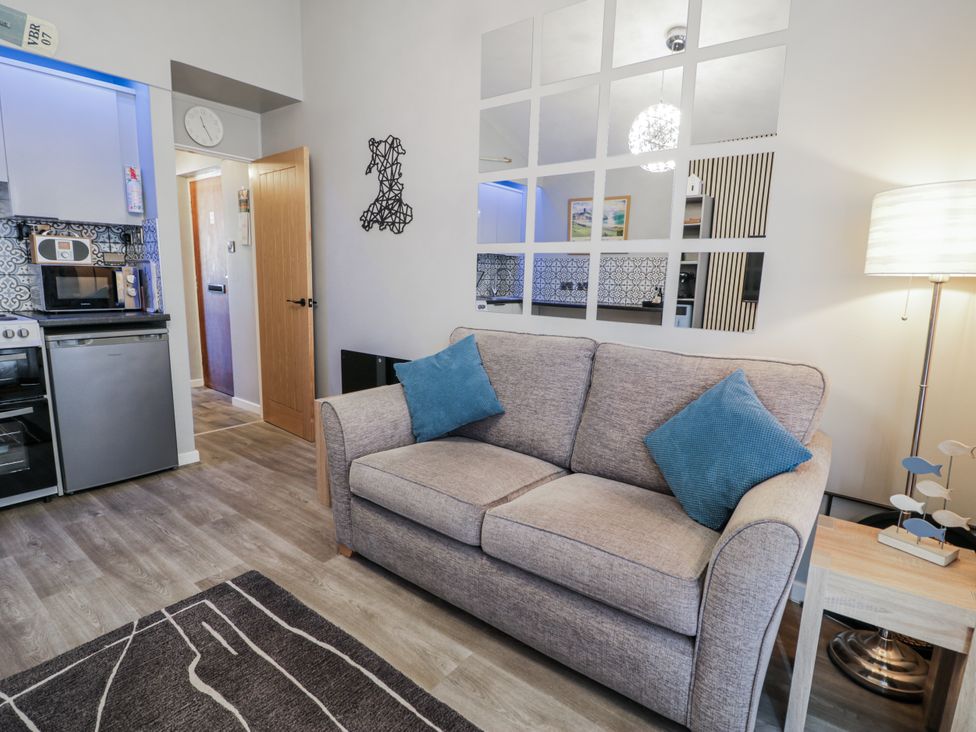 A living room with a sofa and kitchen area at Estuary Escape in Porthmadog