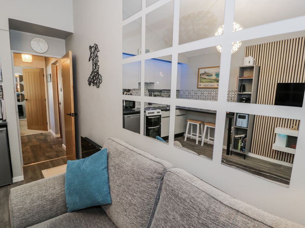 A living room with a couch and kitchen view at Estuary Escape in Porthmadog