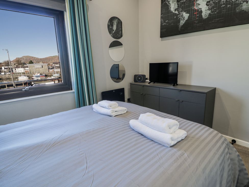 A bedroom with a bed, towels, television, and mirrors at Estuary Escape in Porthmadog