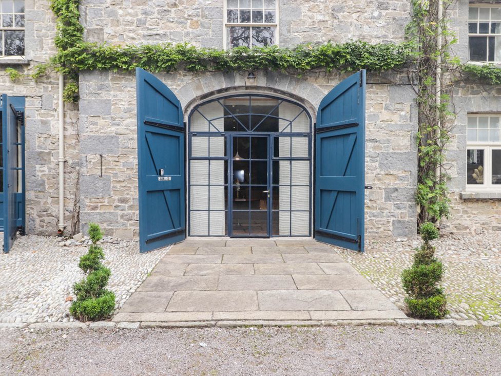 An entrance with blue double doors opening onto a cobblestone pathway at The Carriages in St Athan