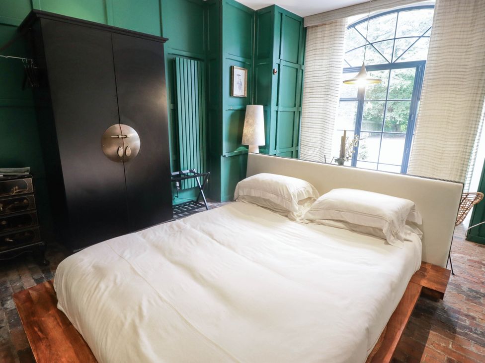 A bedroom with a bed and wardrobe at The Carriages St Athan