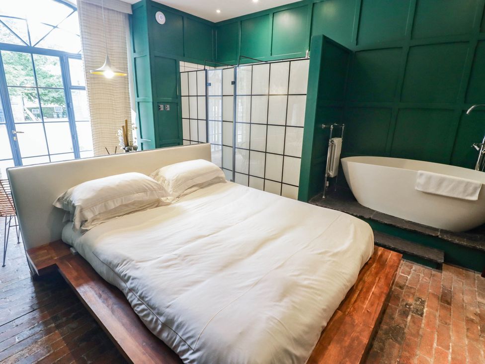 A bedroom with a bed and bathtub at The Carriages St Athan