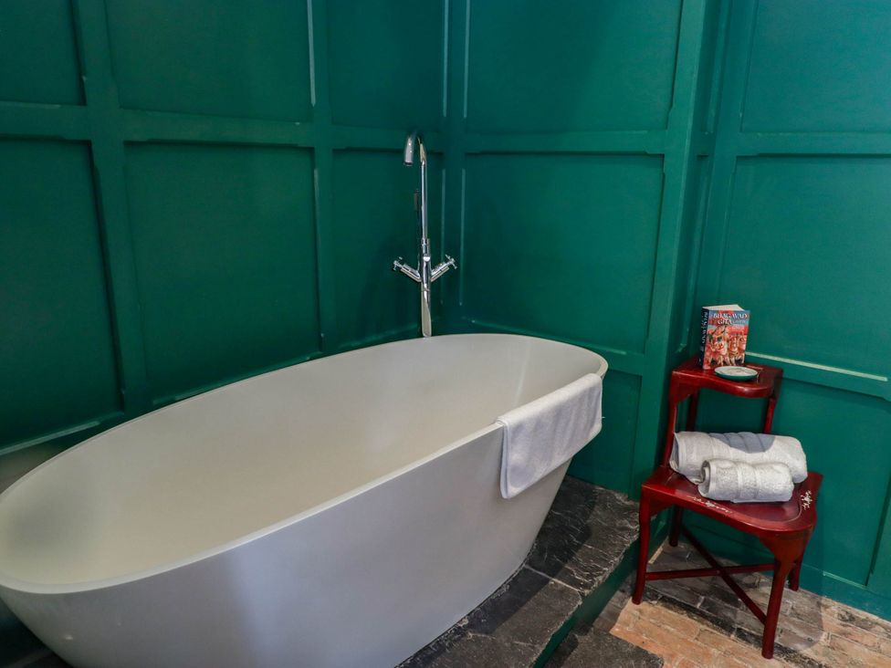 A bathroom with a bathtub and a side table at The Carriages in St Athan