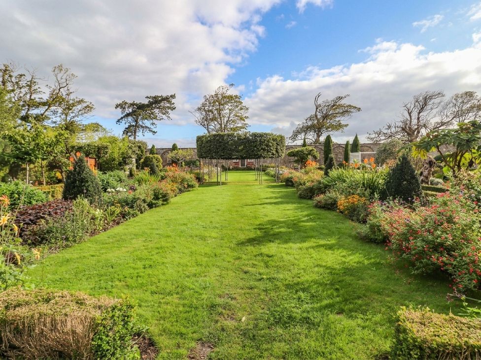 A garden with flower beds and trees at The Carriages St Athan