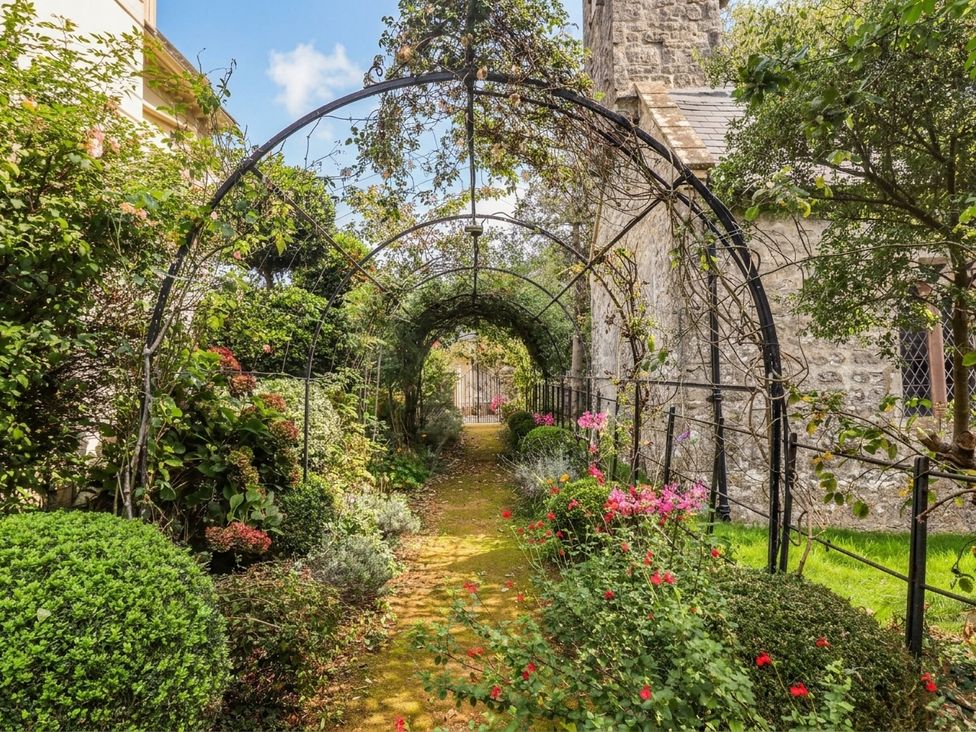 A garden with an archway and pathway at The Carriages St Athan