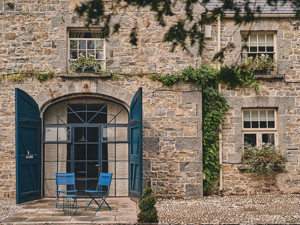 An outdoor seating area with blue chairs and open doors at The Carriages St Athan