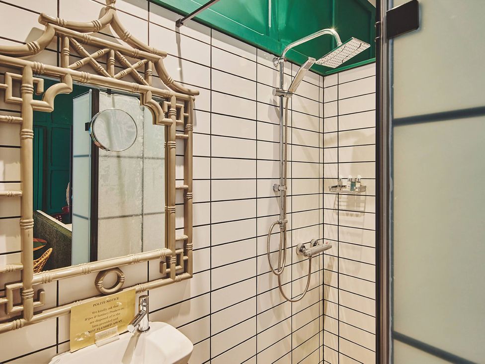 A bathroom with a shower and mirror at The Carriages in St Athan