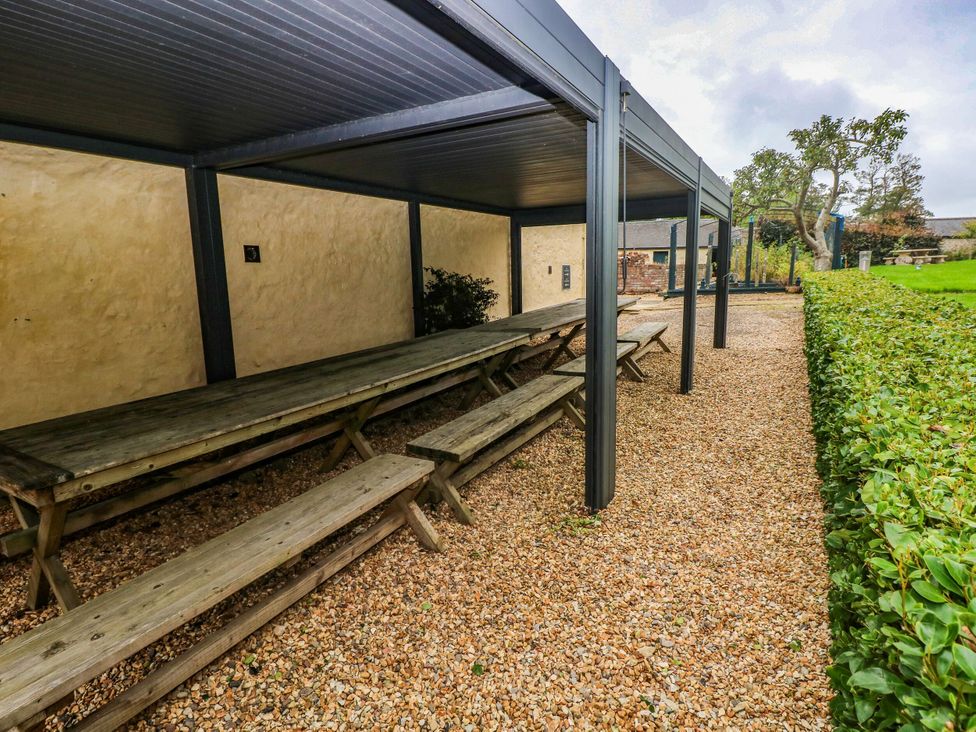 An outdoor seating area with tables and benches at The Carriages St Athan