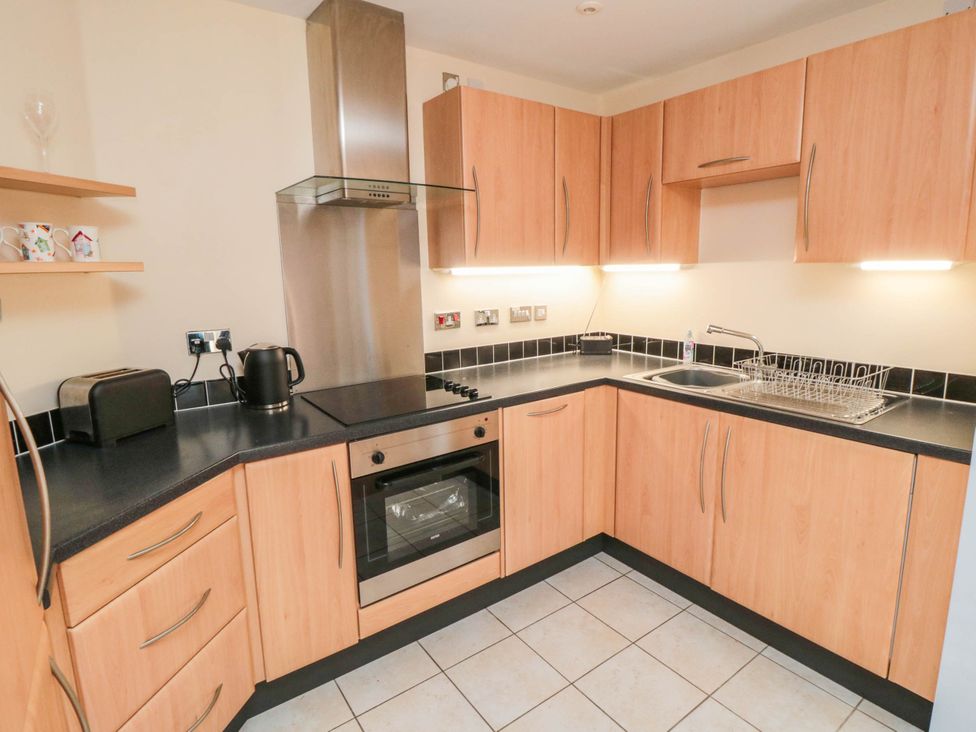 A kitchen with wooden cabinets and appliances at Flat 17
