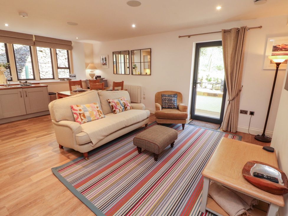 A living room with a sofa and dining area at Deer Wood At Applethwaite Hall Windermere