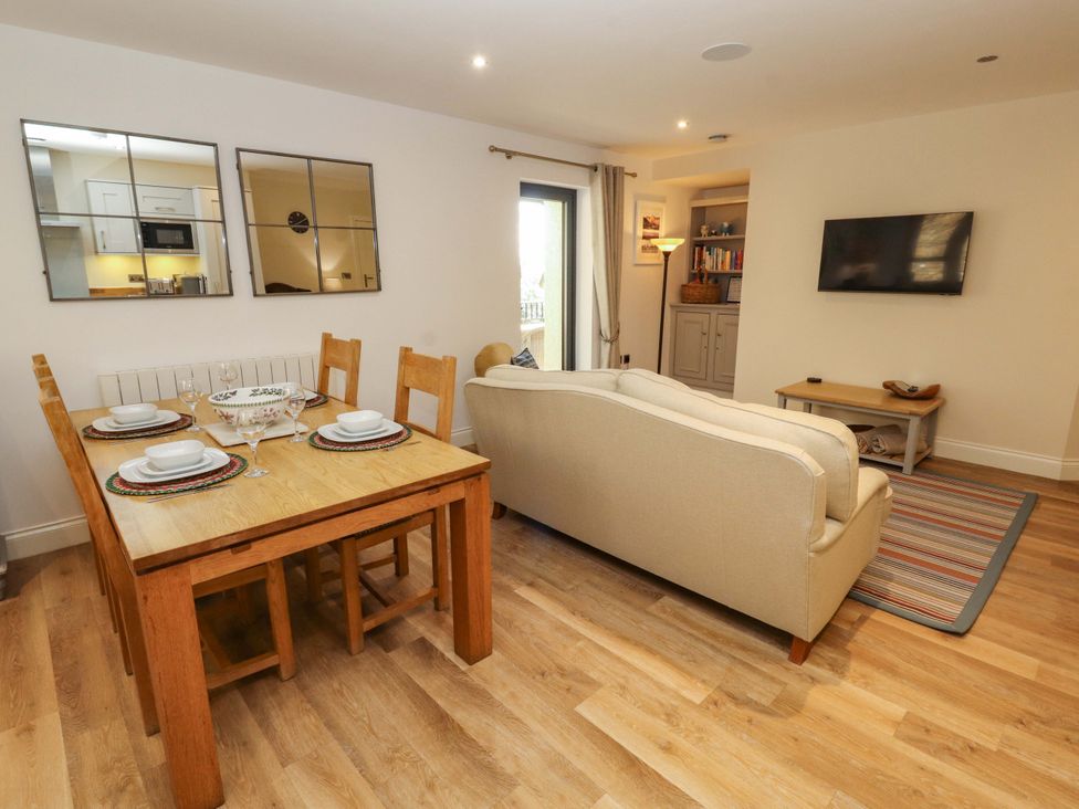 A dining table and sofa in a living room and kitchen area at Deer Wood At Applethwaite Hall Windermere