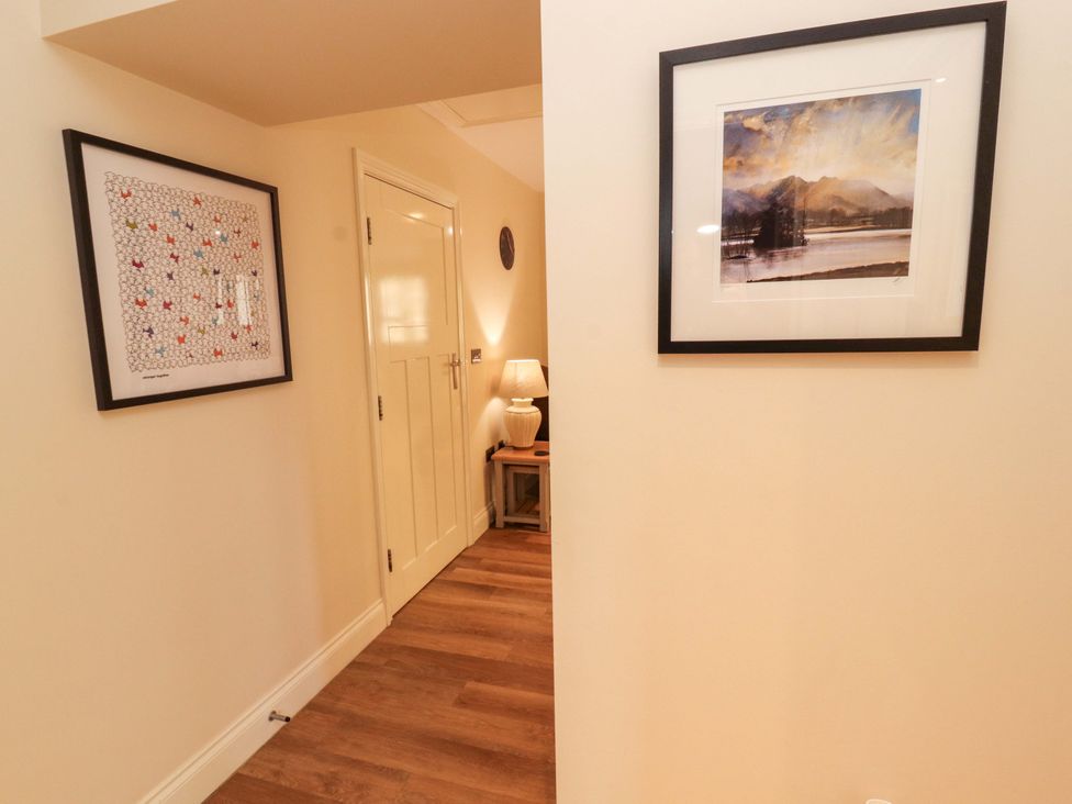 A hallway with a door and framed pictures at Deer Wood At Applethwaite Hall in Windermere