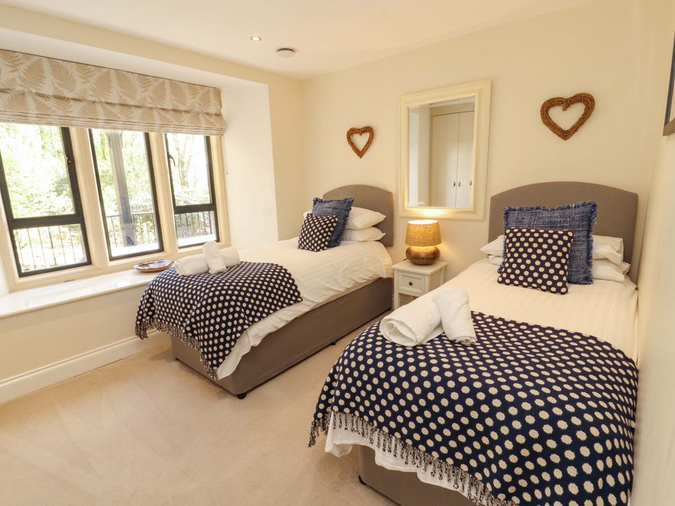 A bedroom with two beds and a bedside table at Deer Wood At Applethwaite Hall Windermere