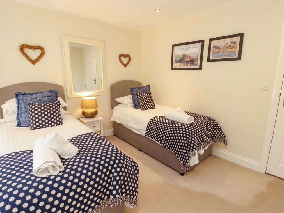 A bedroom with two single beds and a mirror at Deer Wood At Applethwaite Hall in Windermere