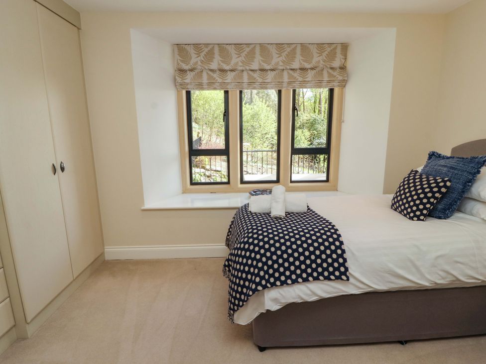 A bedroom with a bed and wardrobe at Deer Wood At Applethwaite Hall in Windermere