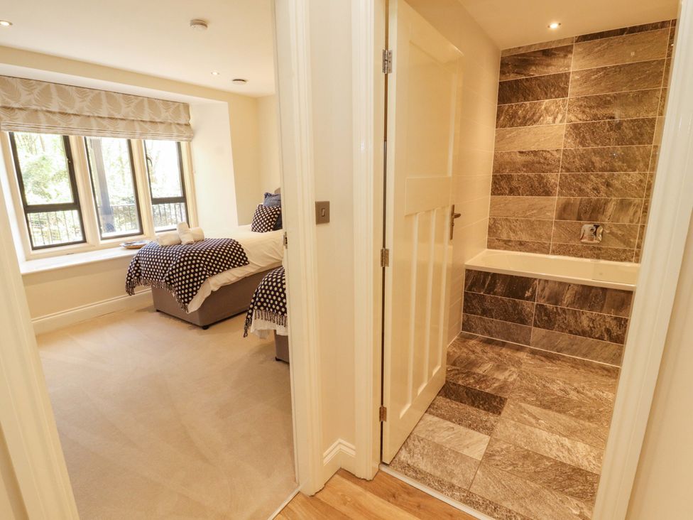 A bathroom with a bathtub and a doorway leading to a bedroom at Deer Wood At Applethwaite Hall Windermere