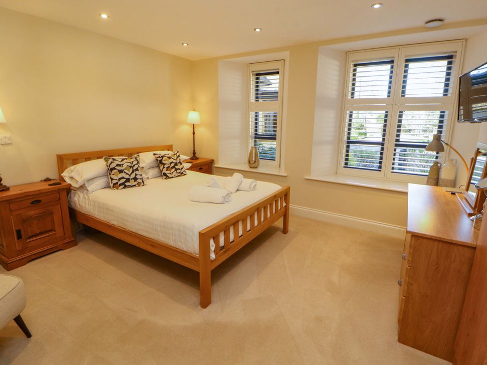 A bedroom with a bed and side tables at Deer Wood At Applethwaite Hall in Windermere