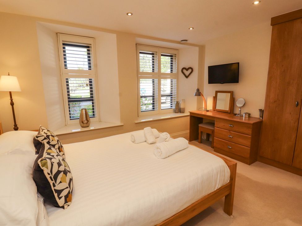 A bedroom with a bed and dresser at Deer Wood At Applethwaite Hall in Windermere
