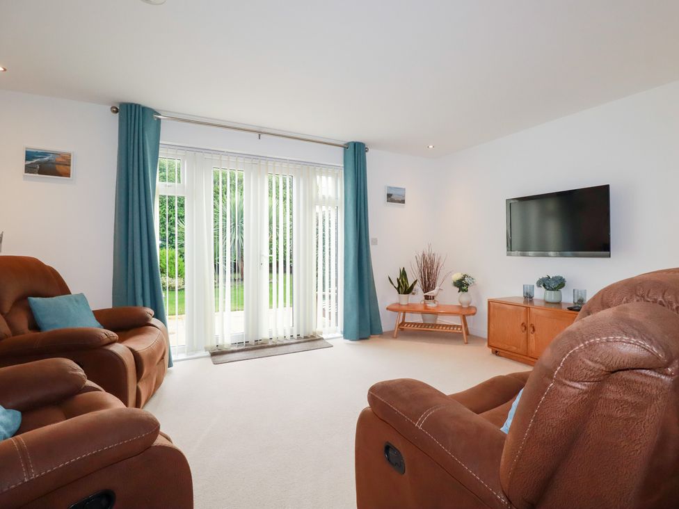 A living room with a sofa and television at Blissful Ocean Breeze in Perranporth