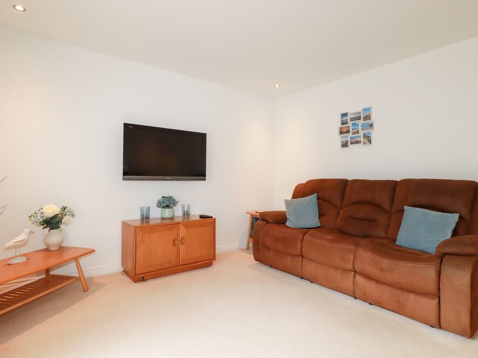 A living room with a sofa and television at Blissful Ocean Breeze in Perranporth