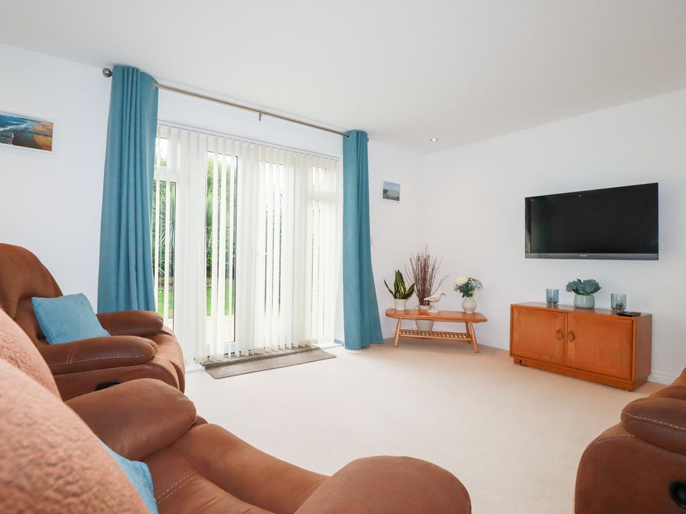 A living room with a sofa and television at Blissful Ocean Breeze in Perranporth