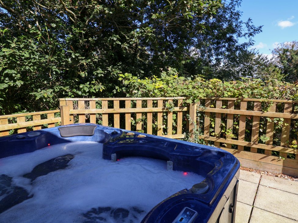 A hot tub overlooking a fenced area with plants at Seagrass in Bideford
