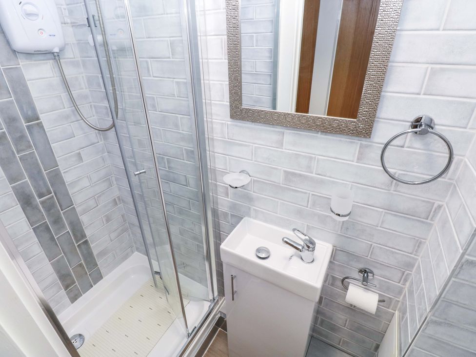 A bathroom with a shower, sink, and mirror at 3 Devon Court in Pembroke