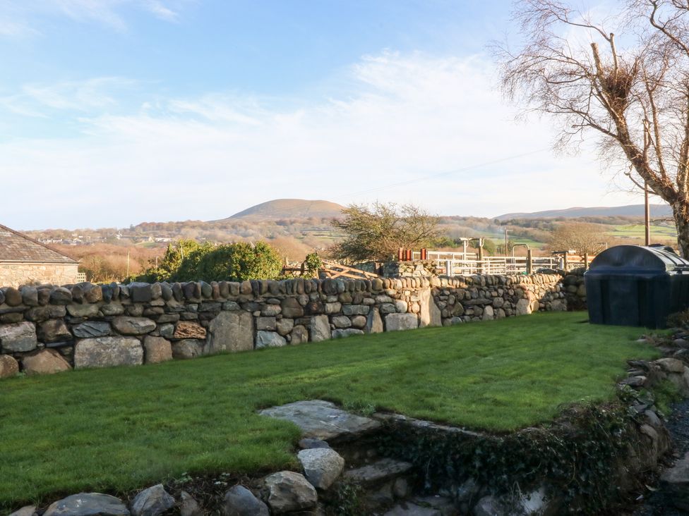 A garden with a stone wall and shed at Yr Hen Felin in Dyffryn Ardudwy