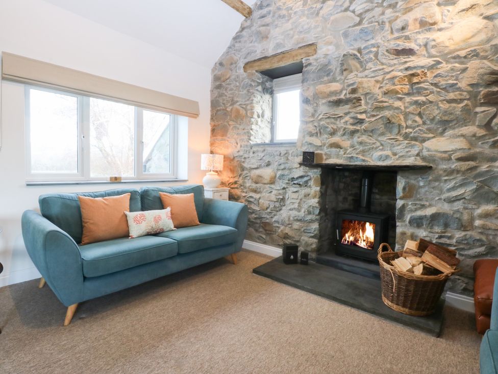 A living room with a sofa, fireplace, and windows at Yr Hen Felin in Dyffryn Ardudwy