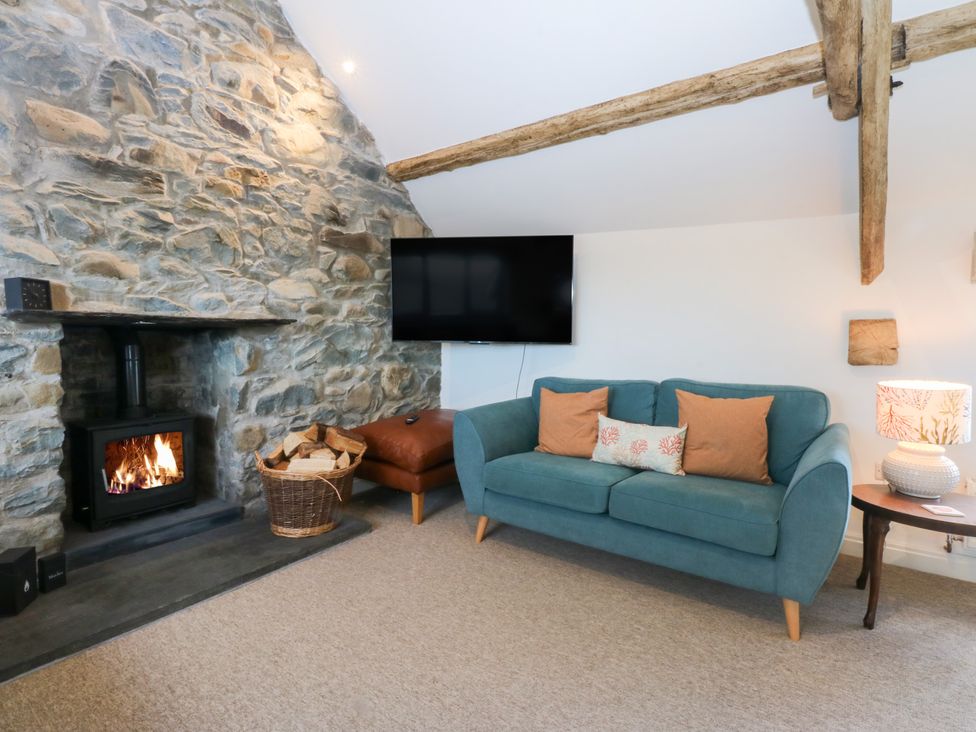 A living room with a sofa and wood-burning stove at Yr Hen Felin in Dyffryn Ardudwy