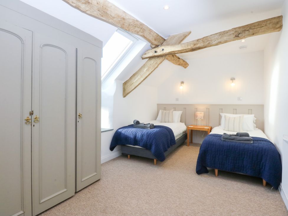 A bedroom with two beds and a wardrobe at Yr Hen Felin in Dyffryn Ardudwy