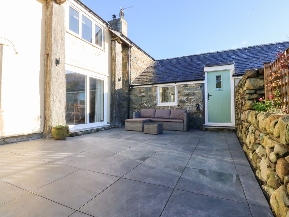 A patio area with a sofa and door at Yr Hen Felin in Dyffryn Ardudwy