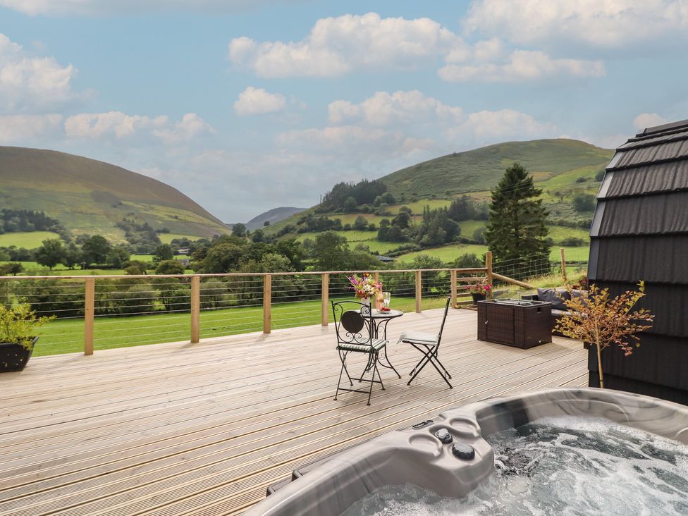 A deck with a hot tub and seating area at Caban Tirion near Dinas Mawddwy