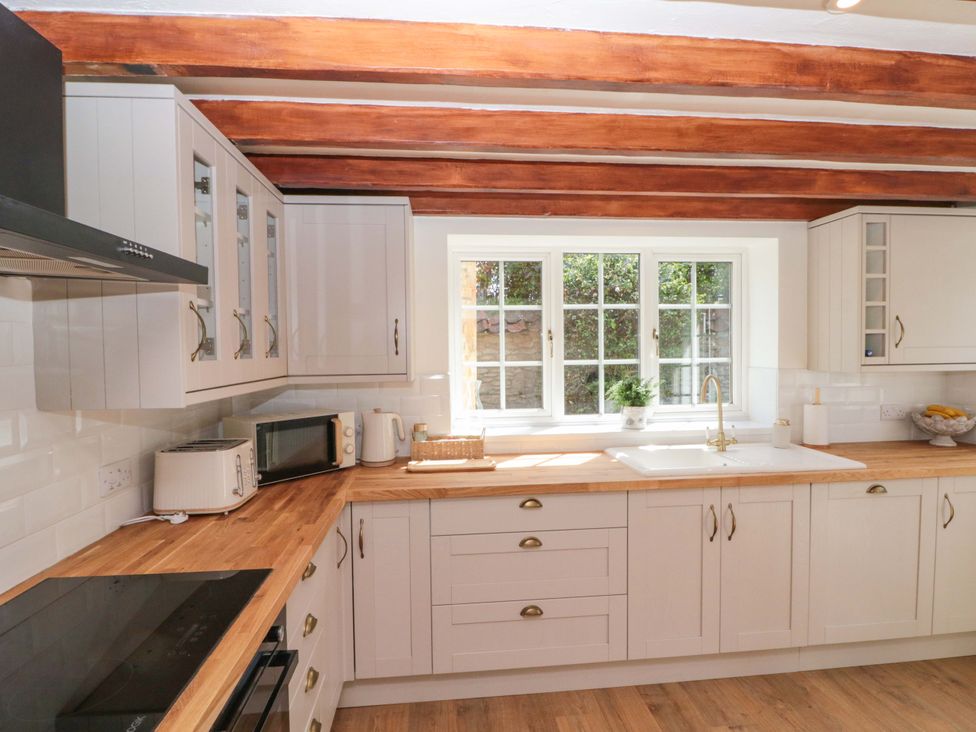 A kitchen with cabinets and appliances at Rose Cottage in East Ayton