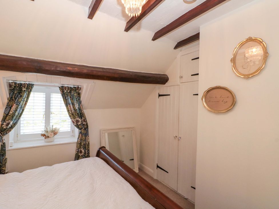 A bedroom with a bed and window featuring curtains at Rose Cottage East Ayton