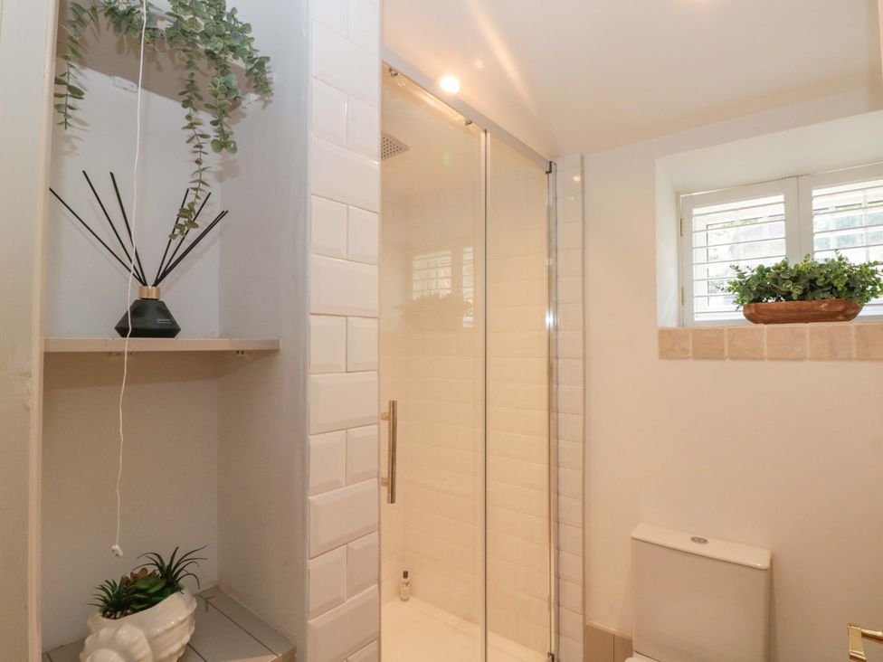A bathroom with a shower, toilet, and shelf at Rose Cottage in East Ayton